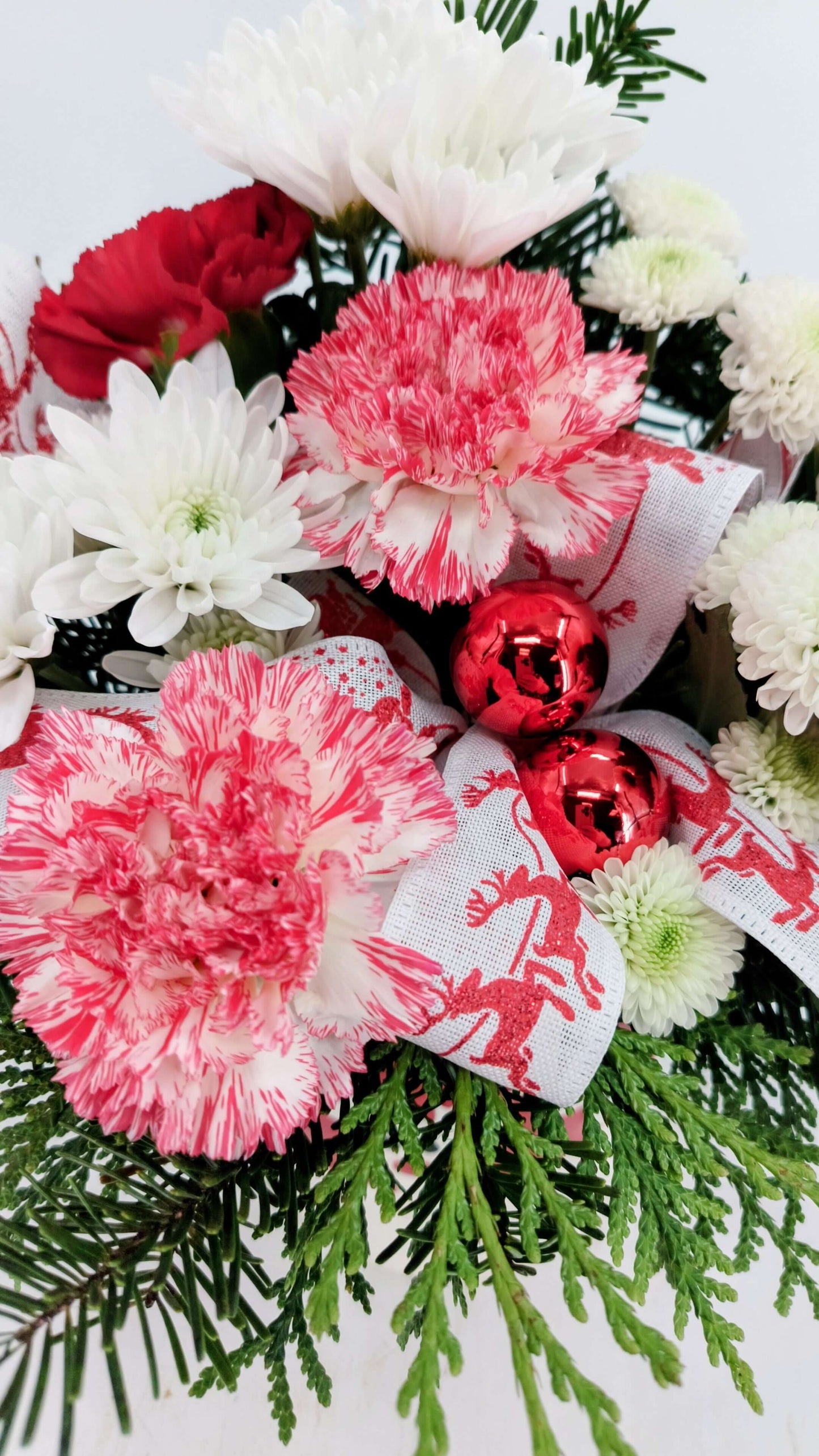 Reindeer Cheer festive flower arrangement with red and white blooms in a whimsical ceramic container.